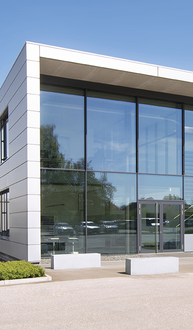 Gewerbliches Objekt mit Glasfront und zweiflügeliger Eingangstür aus Aluminium. Verriegelungen und Rahmenteile von FUHR für Aluminium- und Stahltüren. 